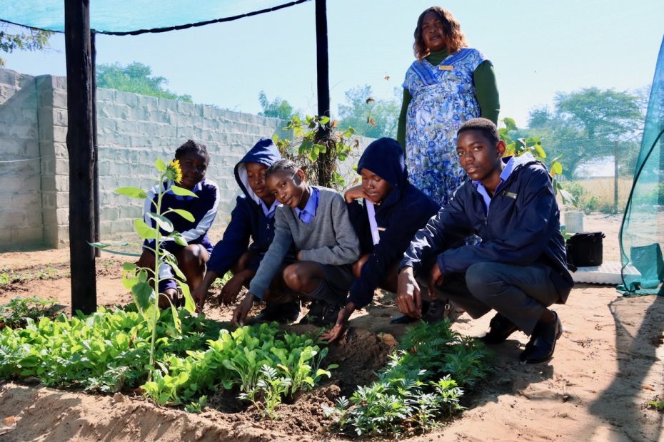 School learners with their female teacher pose for a photo in a garden