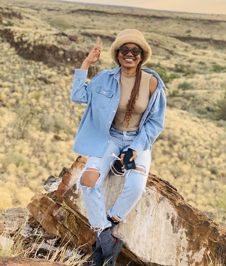 A woman sitting on a rock and smling.