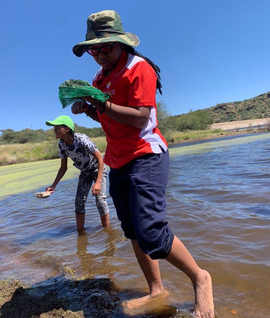 Two people checking small nets in a lake.