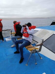 Man with binoculars on a boat.