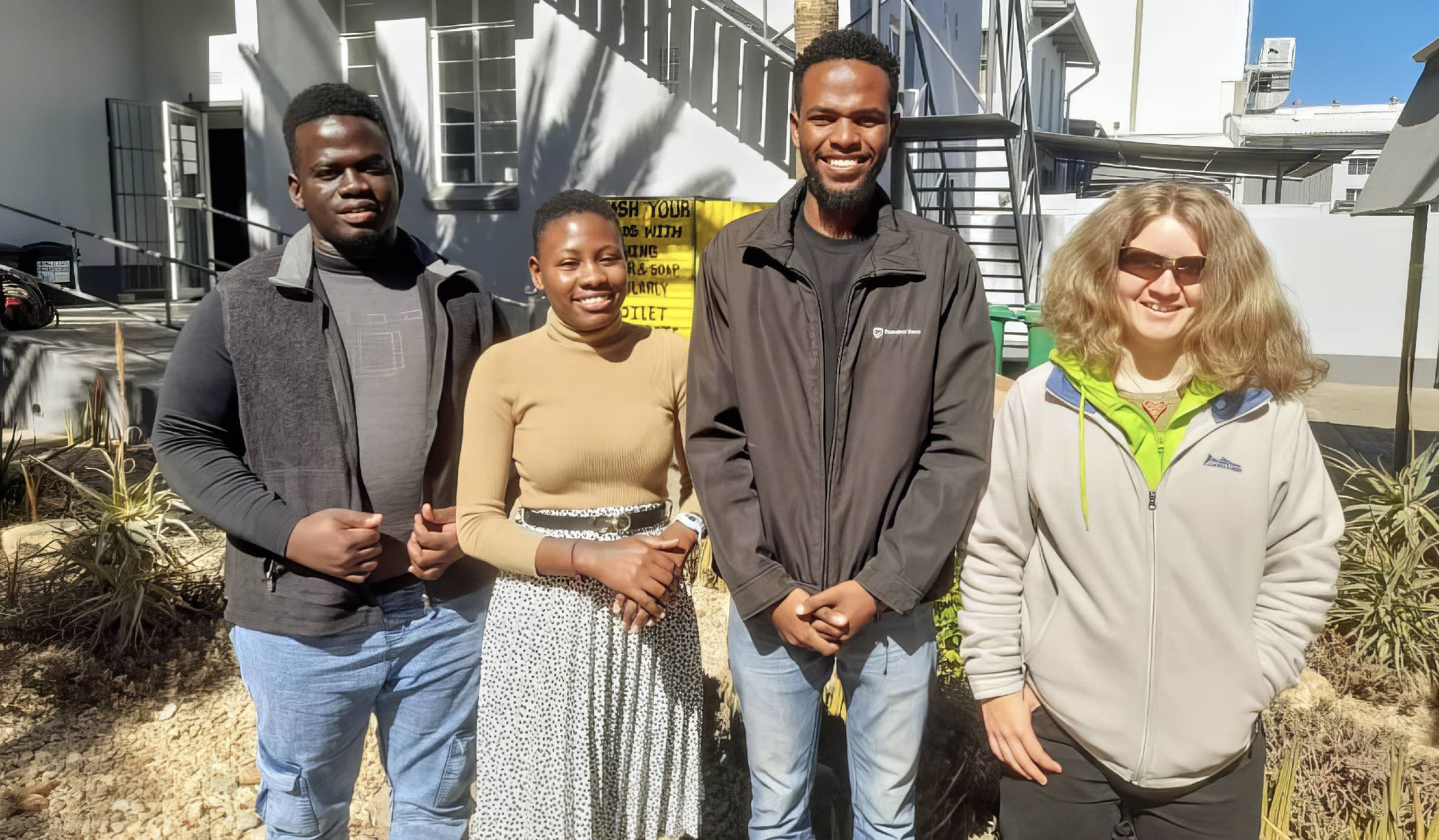 Two men and two women pose in the back garden of the NCE offices.