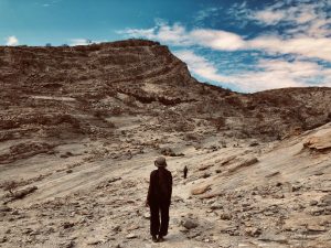 A lady standing in a valley, looking at a hill top