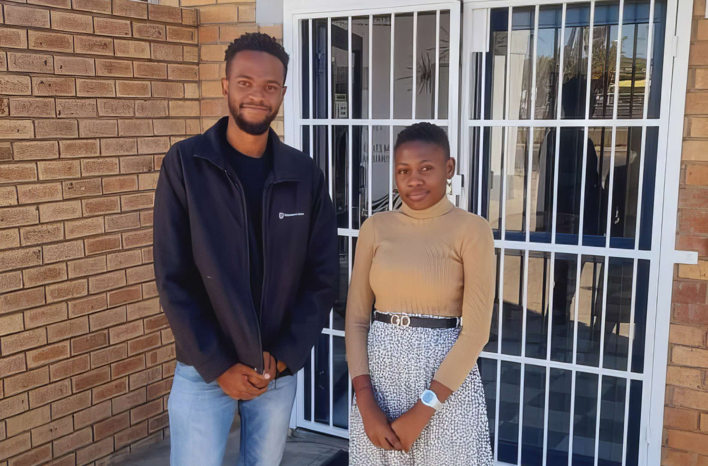A man and a woman standing outside a doorway.