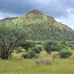 A mountain with green vegetation with a rain cloud hanging on its top