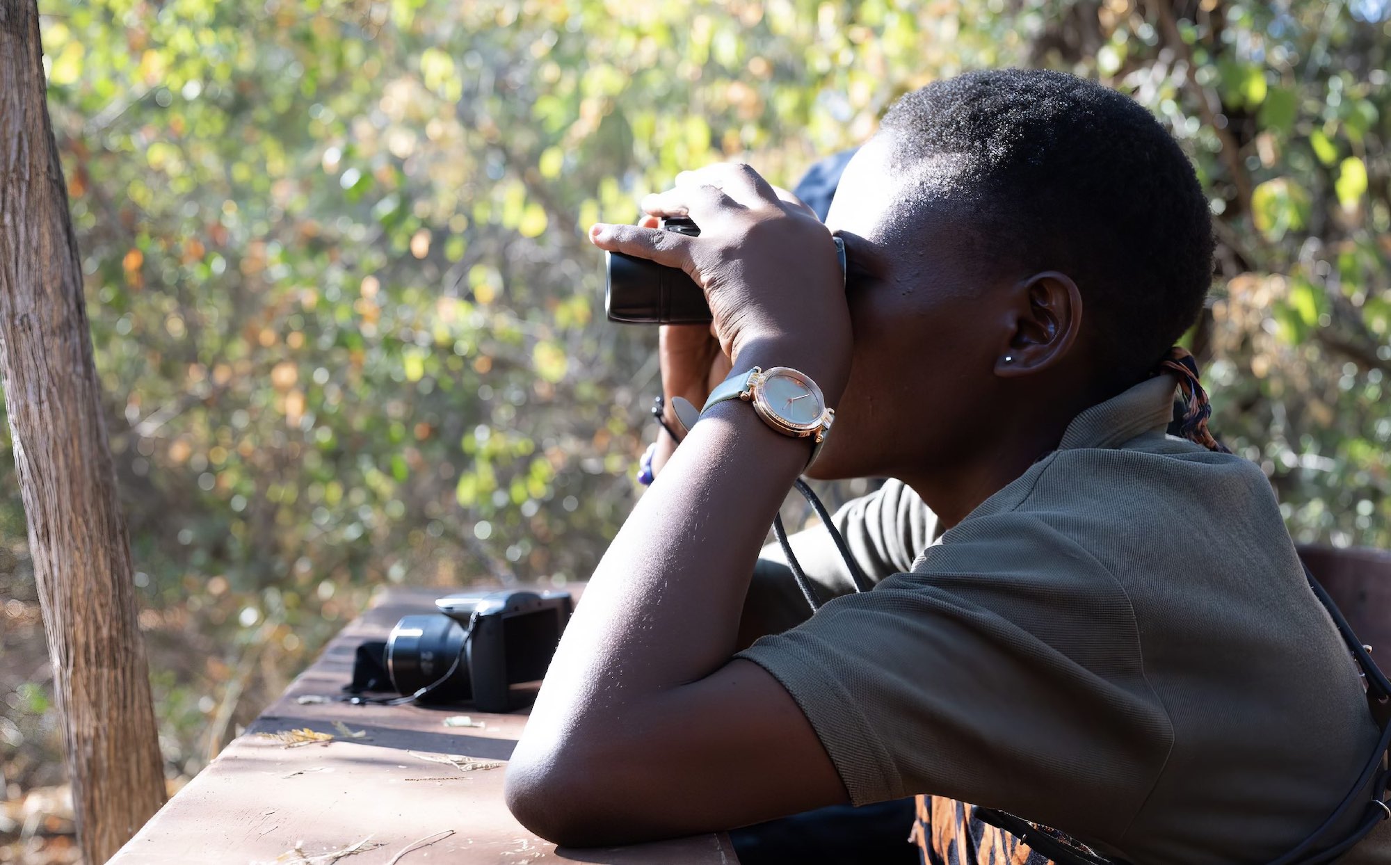 Side view of a woman looking through binoculars.